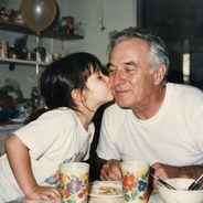 A little girl kissing her grandfather on the cheek at the kitchen table