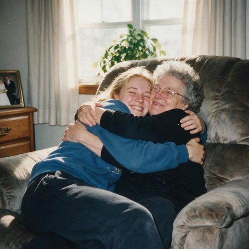 A young woman hugging her grandmother in a cosy armchair