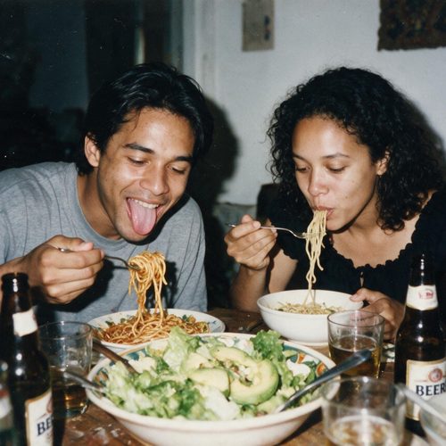 A couple laughing over a big plate of spaghetti at dinner